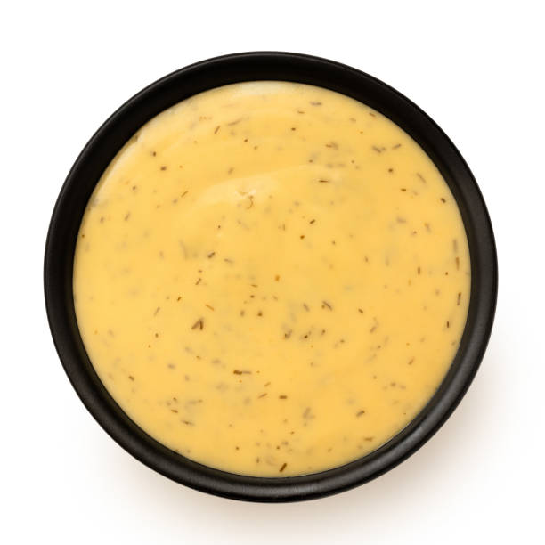 Honey and mustard sauce with dill in a black ceramic bowl. Top view.