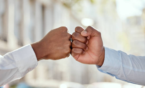 shot of two unrecognizable businesspeople giving each other a fist bump in the city - zoom victory imagens e fotografias de stock