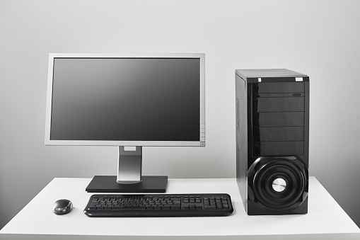 Desktop pc, computer tower with flat screen monitor, keyboard and mouse on white desk