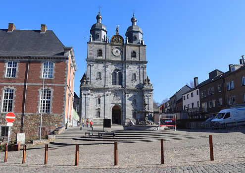 SAINTE HUBERT, BELGIUM, 3 MARCH 2022: View of the Basilica of St. Hubert and Abbey Square in the town center of St. Hubert in the Belgian Ardennes. St. Hubert is a popular tourist centre in the province of Luxembourg.
