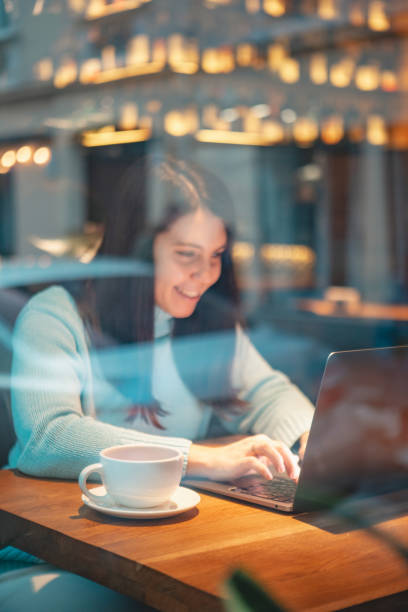 istock smiling woman working on laptop in restaurant drinking tea eating burger 1378853521