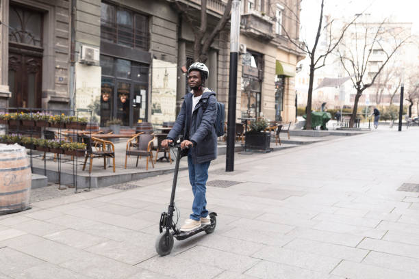 jeune homme afro-américain profitant de la ville, conduisant son scooter - circonscription photos et images de collection