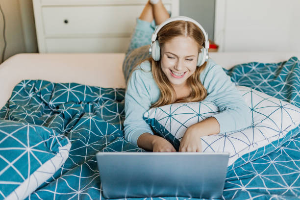 istock Young woman relaxing in bed and using laptop 1378864459