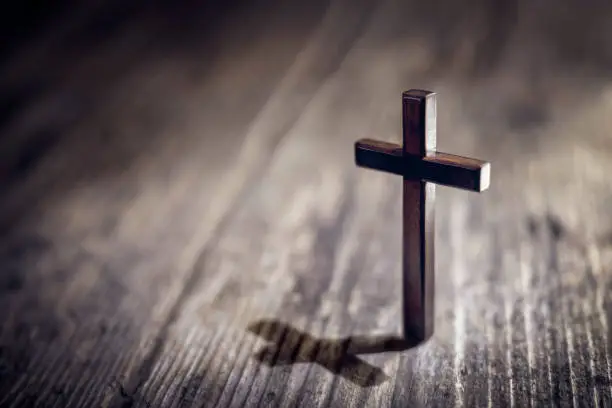 Photo of Religious crucifix cross upright on wooden table background