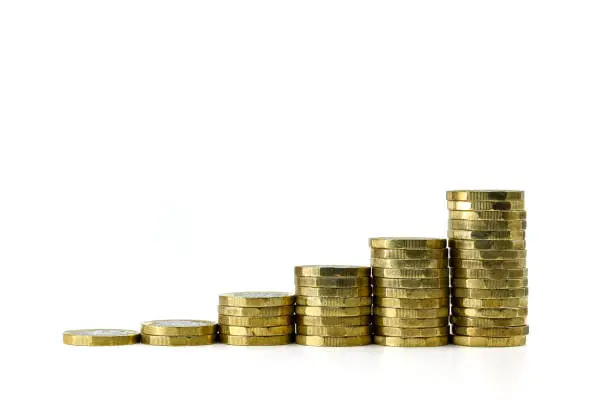 Close up of columns of British one pound coins in ascending order against a plain white background. Graph concept. No people.