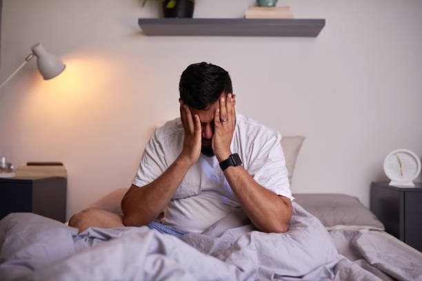 A wide shot of an adult man struggling to wake up in the early morning stock photo