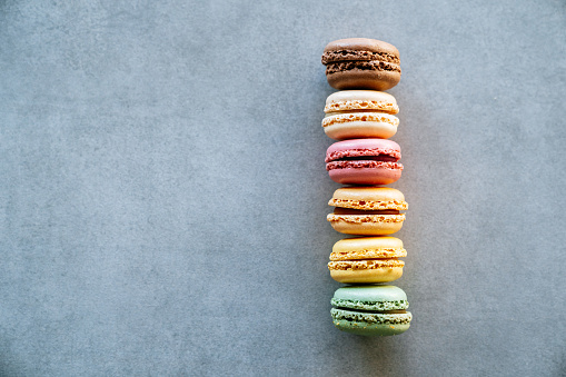 Side view of colorful french macaroons on a concrete background.