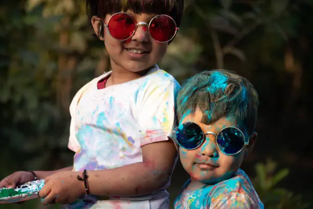 Photo of Indian Festive Theme - Happy Asian Indian Kids Baby Boy And Girl Having Fun With Non Toxic Herbal Holi Color Powder Called Gulal Or Abir Rang Abeer During Hindu Ritual Dol Purnima