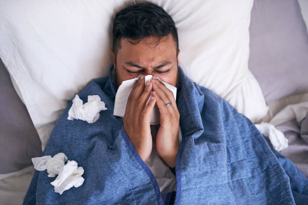 istock An overhead shot of a sick man blowing his nose while lying in bed 1378920919