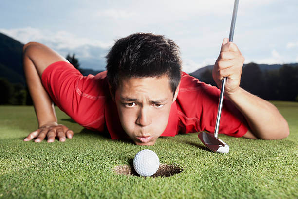 golfista soplando bola en cup. - putting down fotografías e imágenes de stock