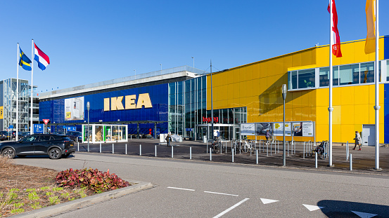 Hengelo, Twente, Overijssel, Netherlands, february 23rd 2022, parked cars and bicycles and a small group of people walking in front of the entrance of the IKEA megastore located at retail park \