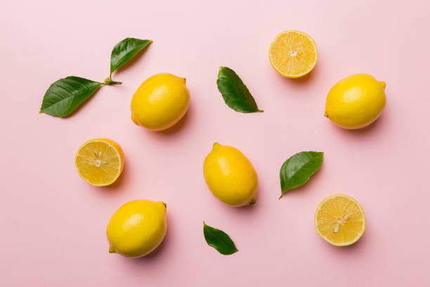 istock Many fresh ripe lemons with green leaves on colored background, top view, space for text 1378974203