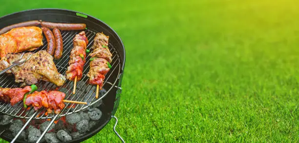 Photo of Delicious grilled meat with vegetables sizzling over the coals on barbecue