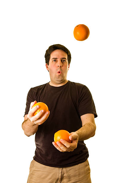 Man in black t-shirt juggles three oranges stock photo