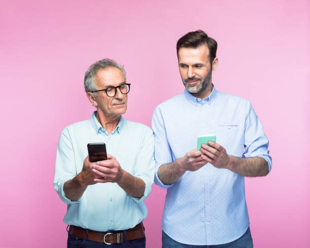 istock Father and son peeking at each other's phones 1379031676