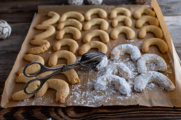 Traditional german christmas cookies called "Vanillekipferl" on a baking sheet coated with powdered sugar.