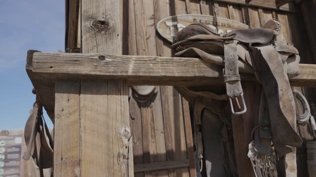 panning old western scene saddle on wood rail