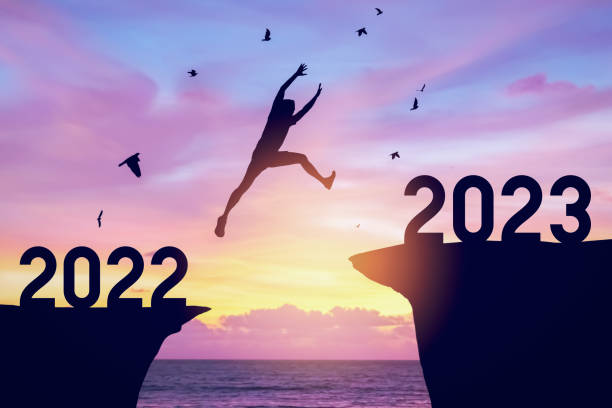 Silhouette man jumping between cliff with number 2022 to 2023 and birds flying at top of mountain. Freedom challenge and travel adventure holiday concept. Silhouette man jumping between cliff with number 2022 to 2023 and birds flying at top of mountain. Freedom challenge and travel adventure holiday concept. Vintage tone filter effect color style. 2023 2022 stock pictures, royalty-free photos & images