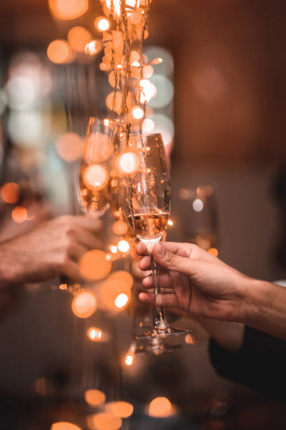 wedding celebratory toast cheers champagne flute between string fairy lights - political party concepts glamour friendship imagens e fotografias de stock