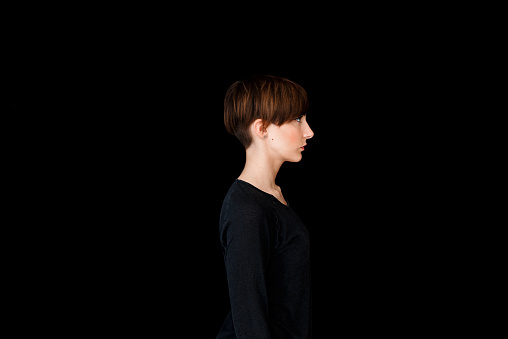 Half length profile portrait of young redhead woman with short hair, turned right