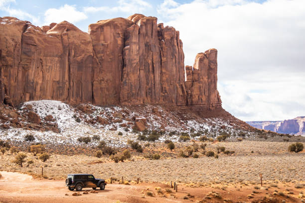 A black off-road car in a southwest desert landscape will large cliffs in the distance stock photo