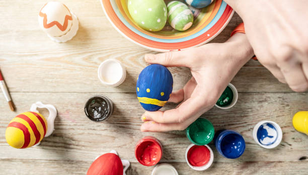 istock Hand with a brush is drawing a colored pattern on an Easter egg. Preparation for the bright Easter holiday 1379158485
