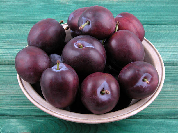 istock Bunch of plums in a bowl on a green table 137915859