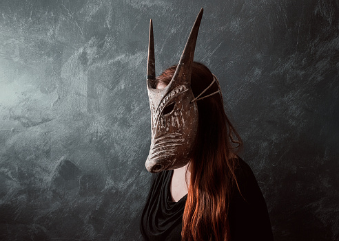 Redhead woman portrait wearing tribal horned mask
