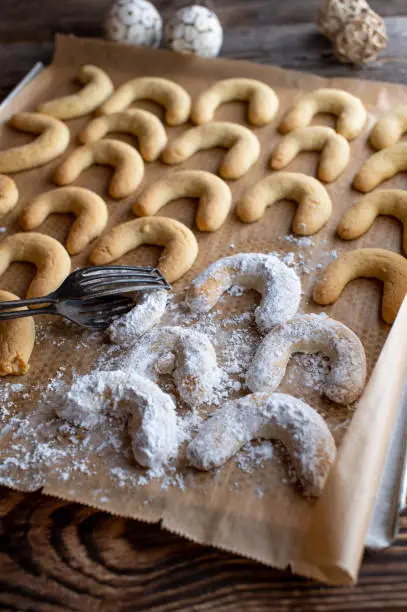 Fresh and homemade baked german christmas cookies, called "Vanillekipferl" served on a baking sheet coated with powdered sugar.