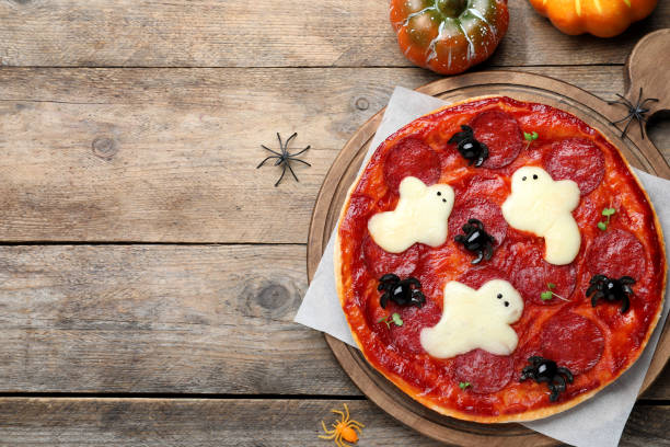 istock Cute Halloween pizza with ghosts and spiders served on wooden table, flat lay. Space for text 1379182595