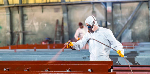 Man painting metal in factory stock photo