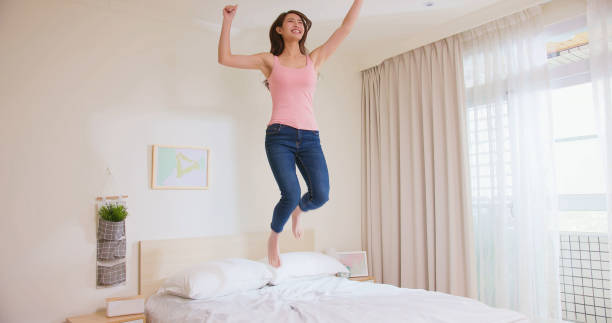 istock Young woman jump on bed 1379191013
