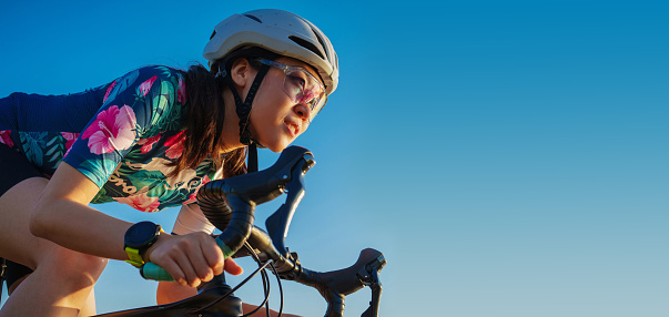 close up young woman riding a bike on blue sky
