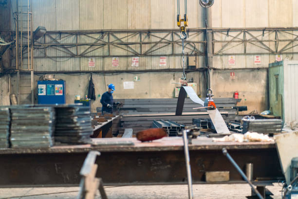 Overhead crane with magnetic grippers lifting steel sheets