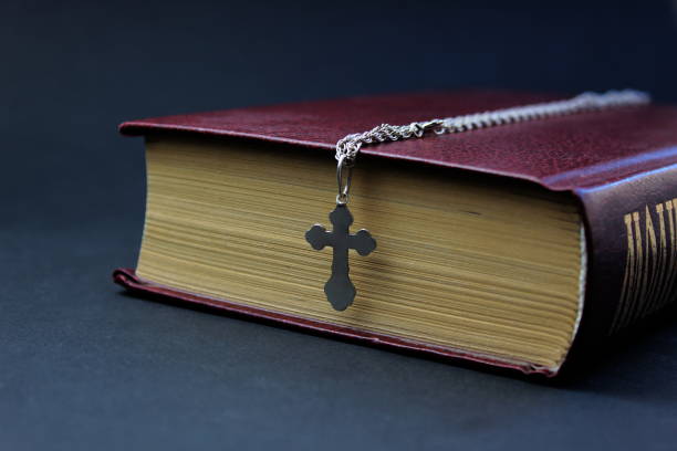 Bible with a cross on a book on black.