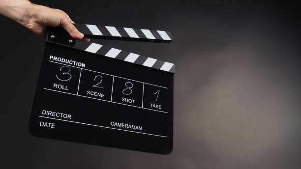 istock A hand is holding a black clapper board or movie slate on black background. It has been written in numbers. 1379215875