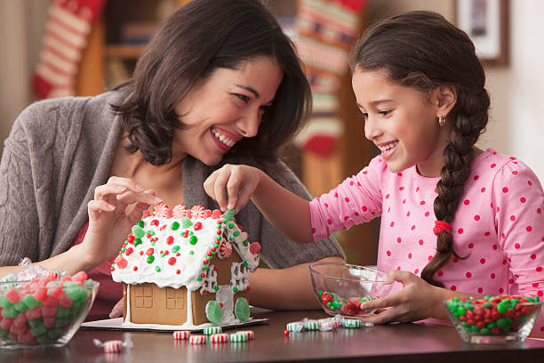 mother and daughter decorating gingerbread house - pepparkakshus bildbanksfoton och bilder