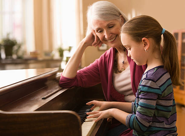 großmutter und enkelin spielen klavier - practicing piano child playing stock-fotos und bilder