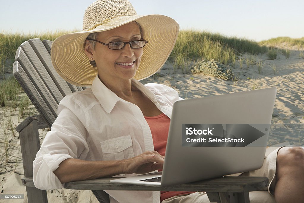 Женщина, сидящая с ноутбуком на открытом воздухе - Стоковые фото Пляж роялти-фри