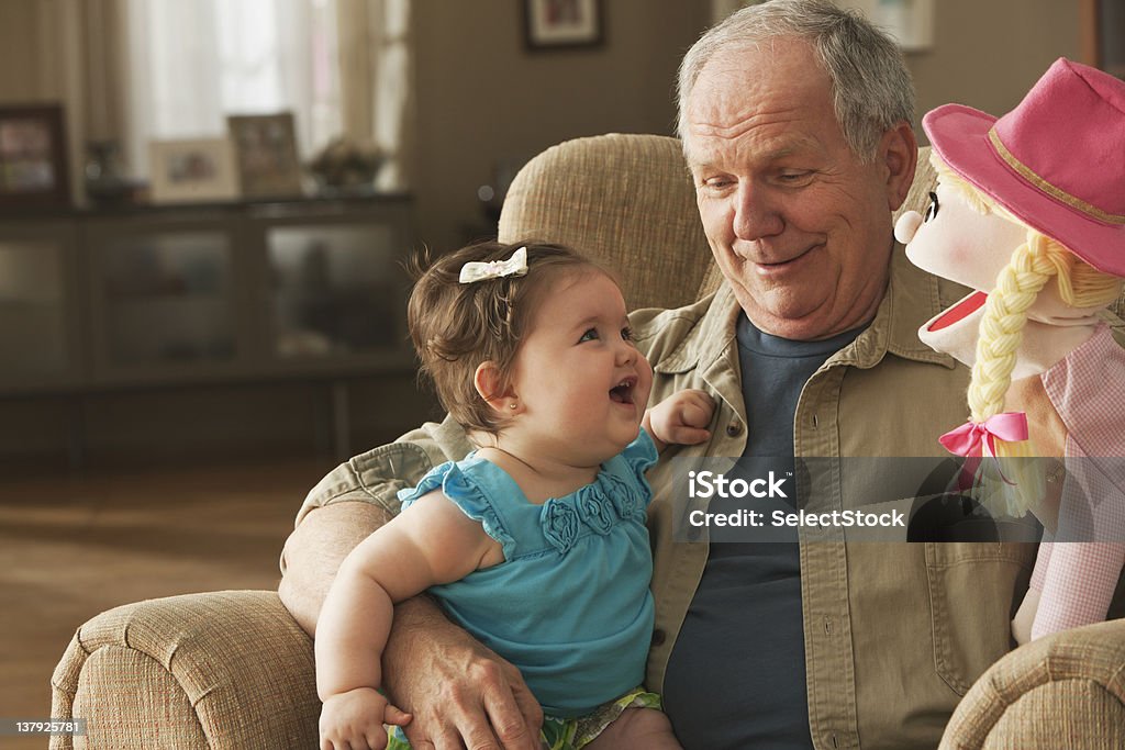 祖父��と赤ちゃん人形の孫娘と遊ぶ - 孫娘のロイヤリティフリーストックフォト