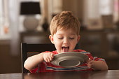Young boy licking plate