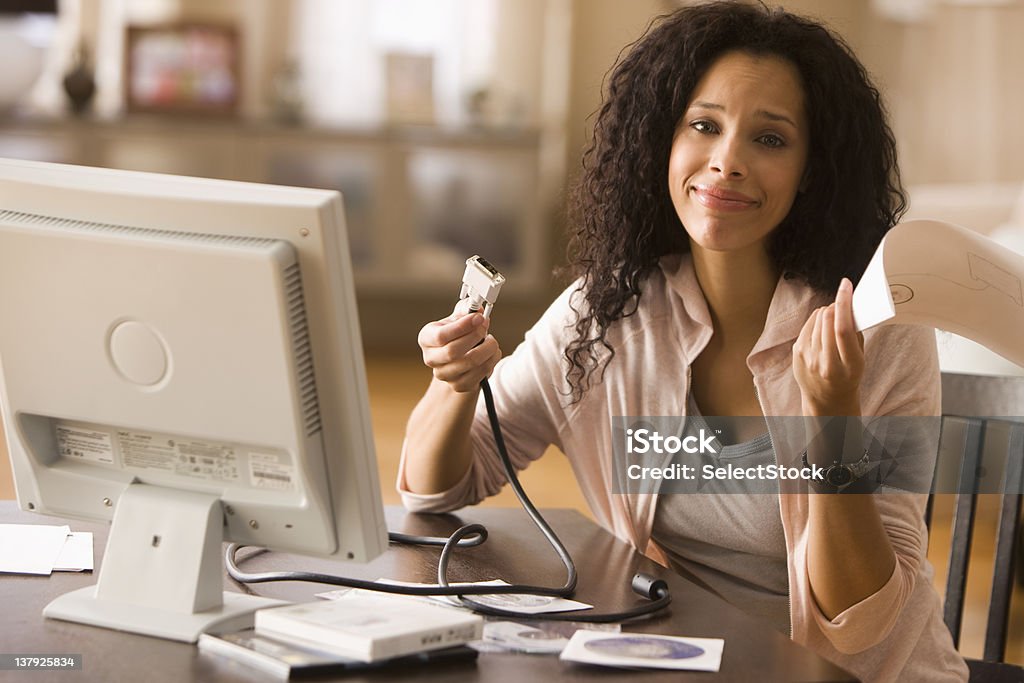 Confused woman reading instructions on how to build PC  25-29 Years Stock Photo