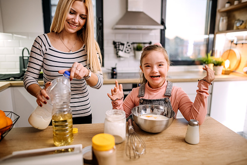 Daughter with Down syndrome helps her mother prepare pancakes