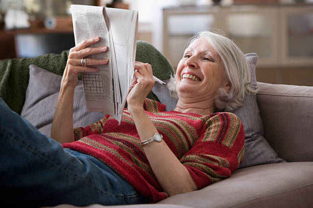 ältere frau, die zeitung kreuzworträtsel - nur seniorinnen stock-fotos und bilder