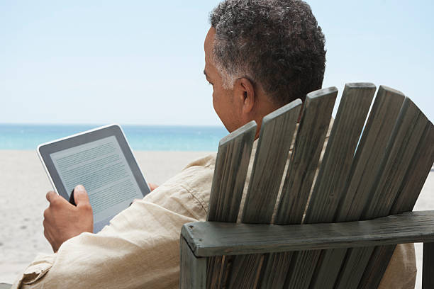 plus homme lisant sur une tablette électronique - reading beach e reader men photos et images de collection