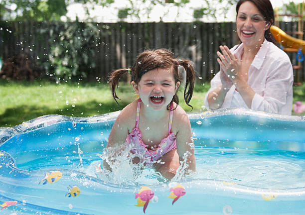 piccolo ragazza che giocano in piscina - splashing color image front view head and shoulders foto e immagini stock