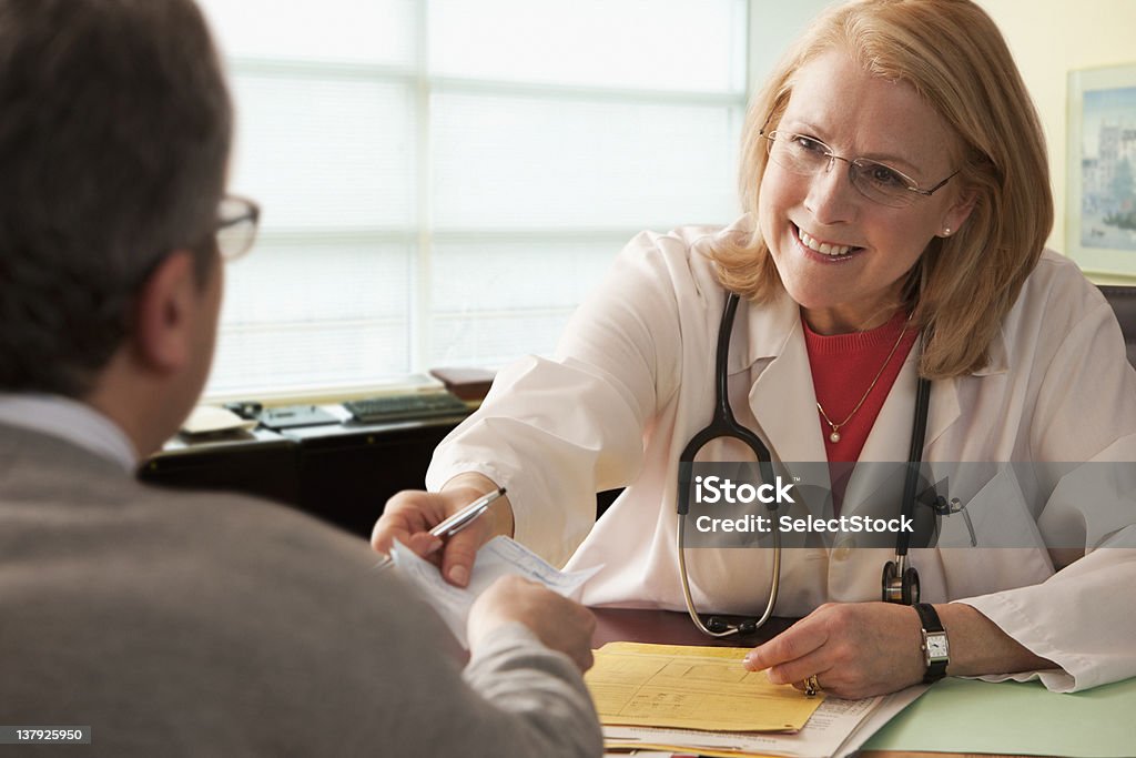 Femme médecin donnant sur ordonnance au patient masculin - Photo de Santé et médecine libre de droits