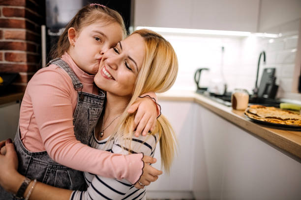 Love between mother and daughter. They hug in the kitchen