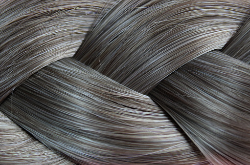 Texture close-up of braided hair gray color background