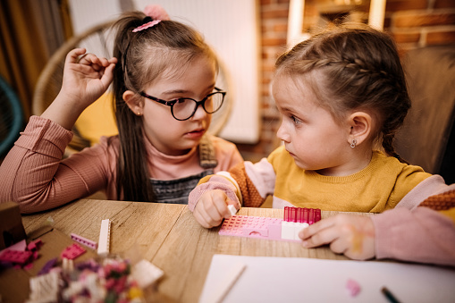 Sisters sit at the table, draw and play